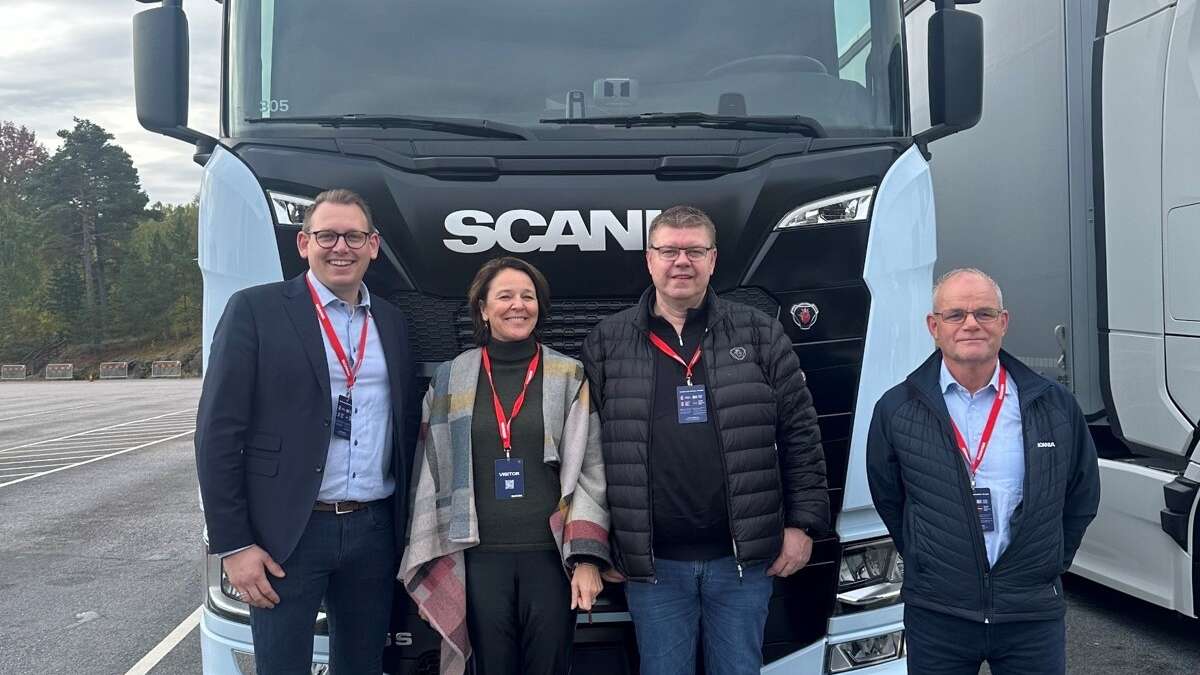 Fire personer foran en elektrisk Scania lastebil