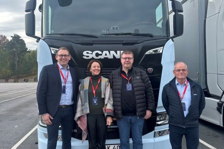 Fire personer foran en elektrisk Scania lastebil