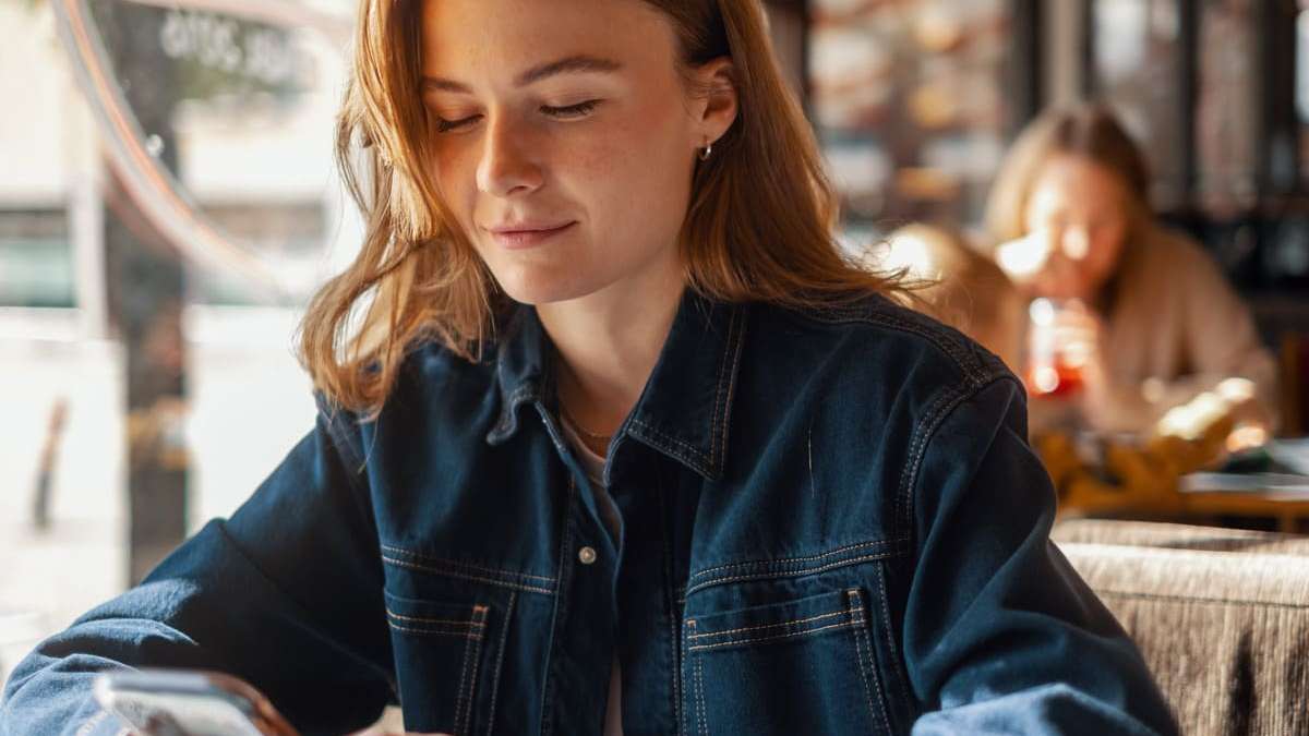 jente sitter med mobilen i hånda