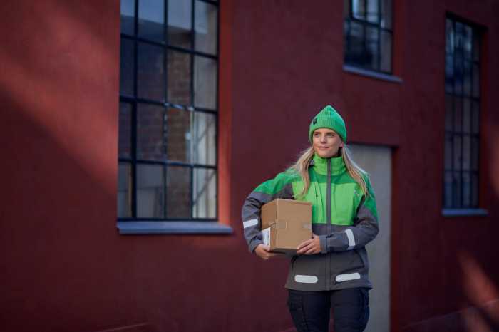 Kvinne i Bring-uniform med pakke under armen.