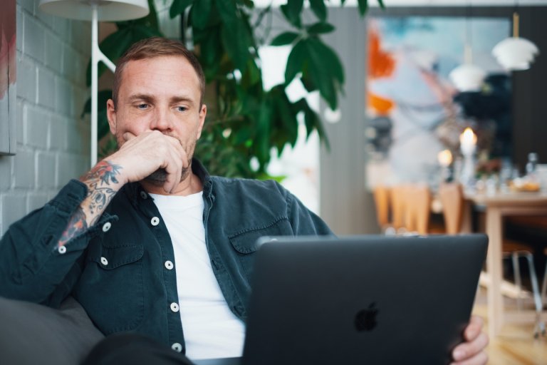 Tenkende mann sitter foran sin laptop