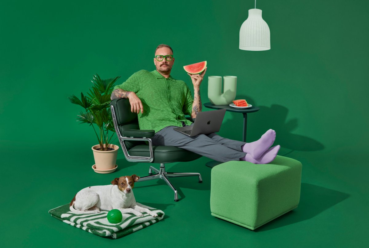 studiobilde mann sitter i stol med mac og vannmelon.