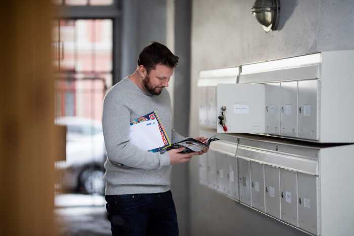 Man som har åpnet postkassen sin og ser på reklamen