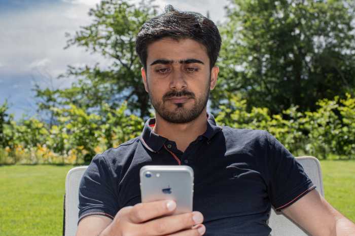 En mann son ser på mobilen sin