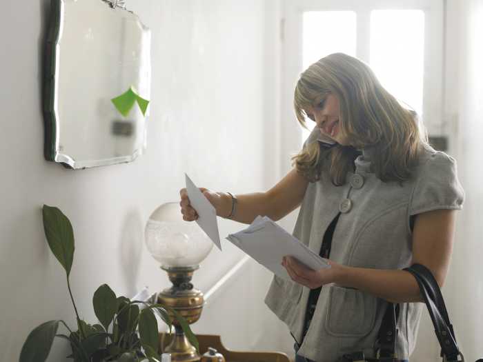 Kvinne som ser på brev mens hun snakker i telefonen