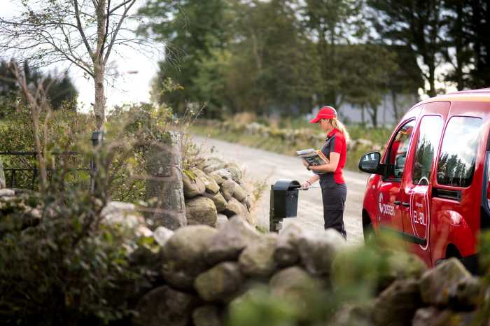 Postbud som leverer post i en svart postkasse