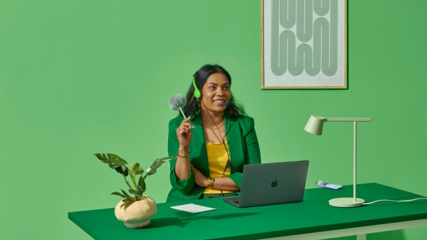 Blid kvinnelig checkout ekspert med høretelefoner foran PC