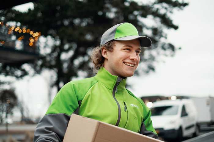 Smilende bringbud med pakke i hendene.