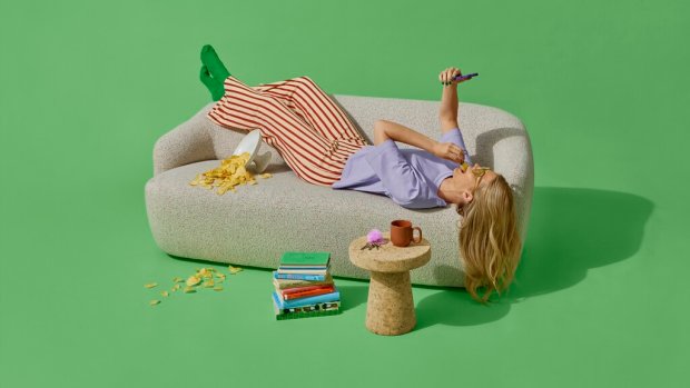 dame ligger på sofa med mobil og venter på pakkelevering