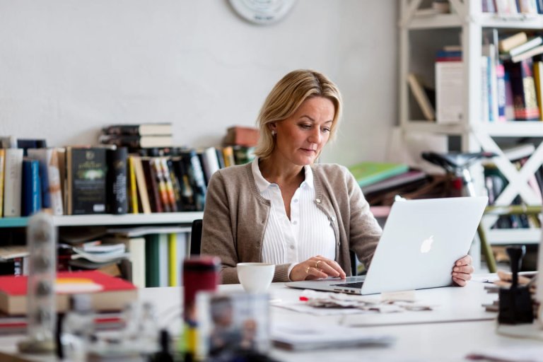 Dame som sitter ved pulten og jobber på pc