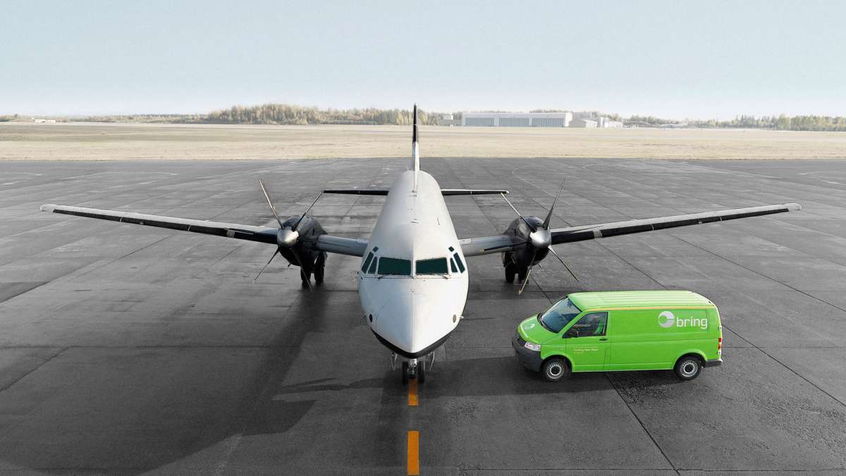 Fly står på flyplass med bring varebil ved siden av.