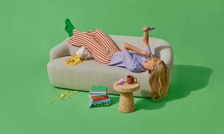 dame ligger på sofa med mobil og venter på pakkelevering