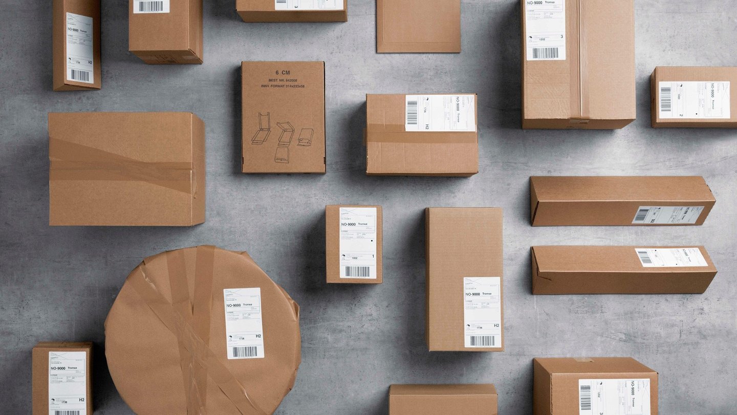 Pakker i gråpapir i ulike format ligger spredd utover et grått gulv.