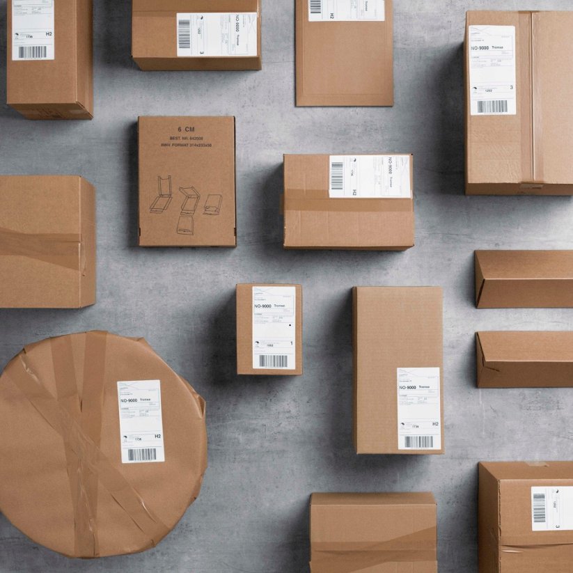 Pakker i gråpapir i ulike format ligger spredd utover et grått gulv.